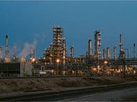 Rohrleitungen, Kolonnen und Rohrbrücken einer großen Chemieanlage im Abendlicht